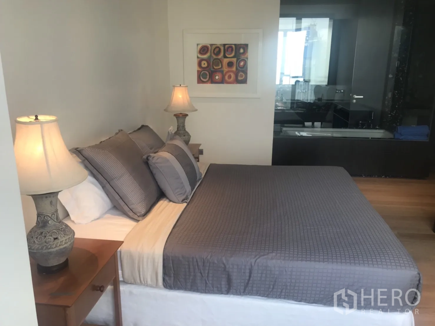 公寓 出租或出售在Khlong Toei, Bangkok - 主卧配双人床、床头灯与玻璃墙浴室