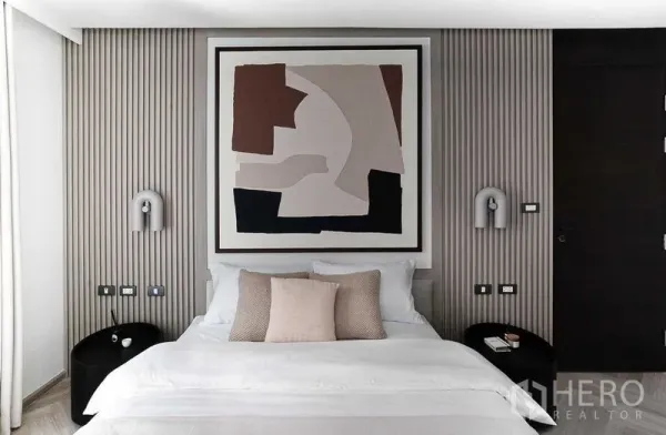 คอนโด ขายในRatchathewi, Bangkok - ภาพใกล้เตียงนอนใหญ่ มีโคมไฟข้างเตียง ผนังลอนและงานศิลป์นามธรรม