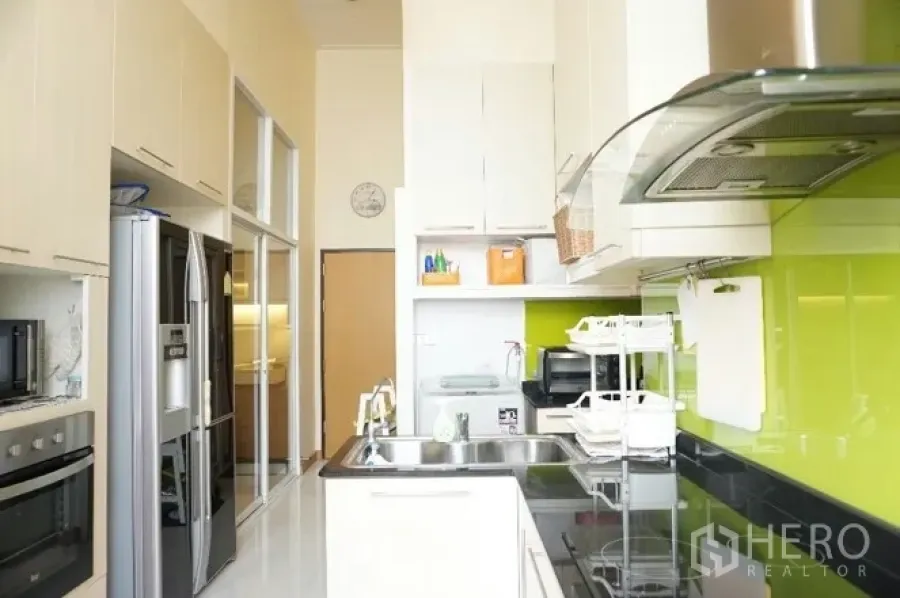 คอนโด ให้เช่าหรือขายในWatthana, Bangkok - ห้องครัวแบบแกลเล่ย์สว่าง พร้อมผนังกระจกสีเขียว เตาอบ ตู้สูง และตู้เย็นประตูคู่