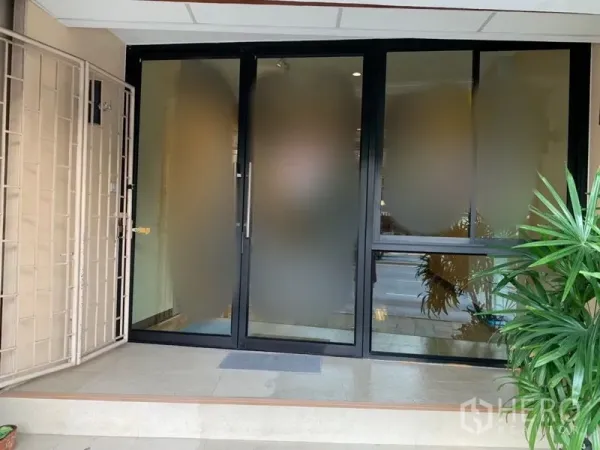 零售空间 出租在Khlong Toei, Bangkok - 一层商铺入口，磨砂玻璃推拉门、台阶与绿植。