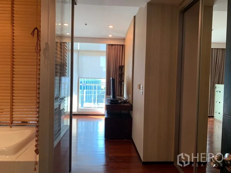 Condominium for rent - Hallway with bathtub behind a glass partition and a bright balcony view ahead.