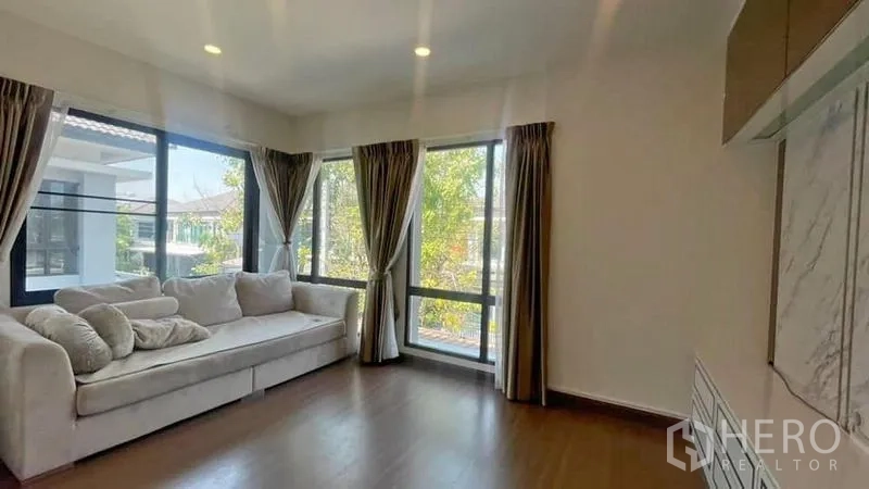 บ้าน ให้เช่าหรือขายในPrawet, Bangkok - ห้องนั่งเล่นมุมบ้าน โซฟา L หน้าต่างสูงจรดเพดาน มองเห็นสวน