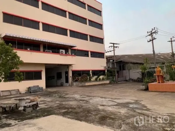 工厂 出租在Samut Prakan - 多层厂办外观，前方为宽阔混凝土场地与装卸入口。