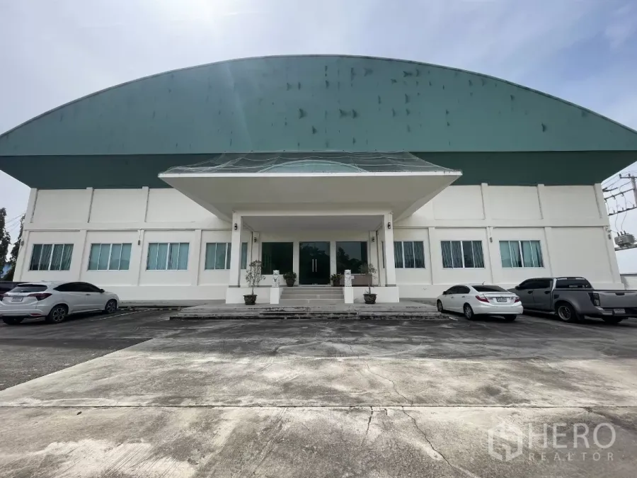 Warehouse for sale in Lat Lum Kaeo, Pathum Thani - Front elevation of a large white warehouse with green arched roof and parking in Lat Lum Kaeo, Pathum Thani.