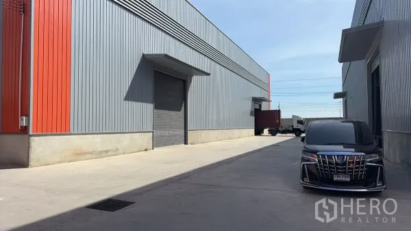 货栈 出租在Bang Bo, Samut Prakan - 现代金属外墙仓库外观，卷闸装卸口，宽阔车道可供卡车进出。