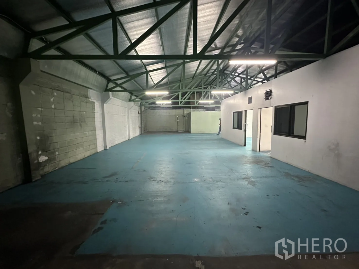 Warehouse for rent in Bang Na, Bangkok - Wide angle of open-plan upper hall with truss roof and blue flooring.
