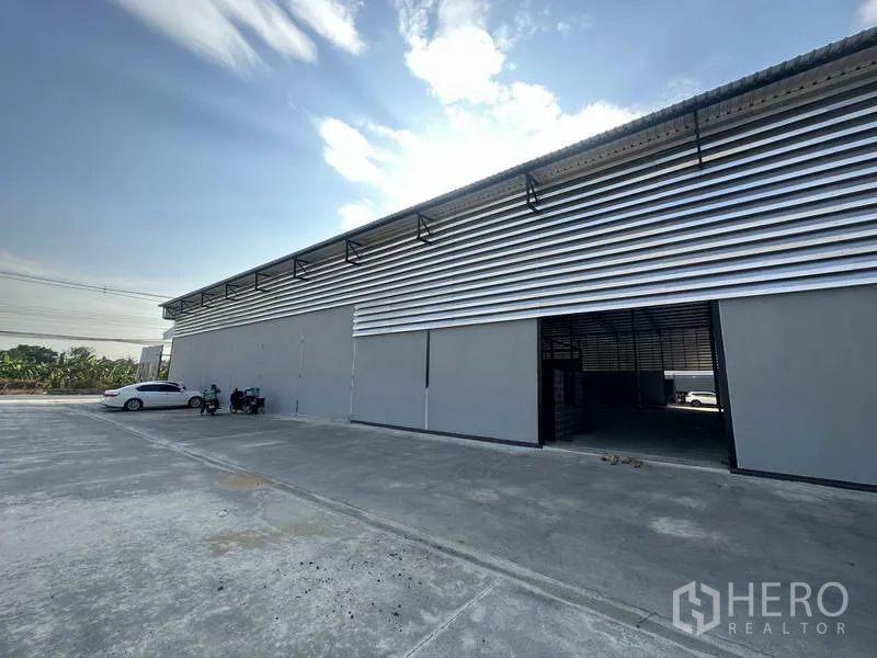 คลังสินค้า ให้เช่าในLam Luk Ka, Pathum Thani - ด้านข้างอาคารมีผนังระบายอากาศ ประตูบานเลื่อน และลานคอนกรีตสำหรับรถบรรทุก