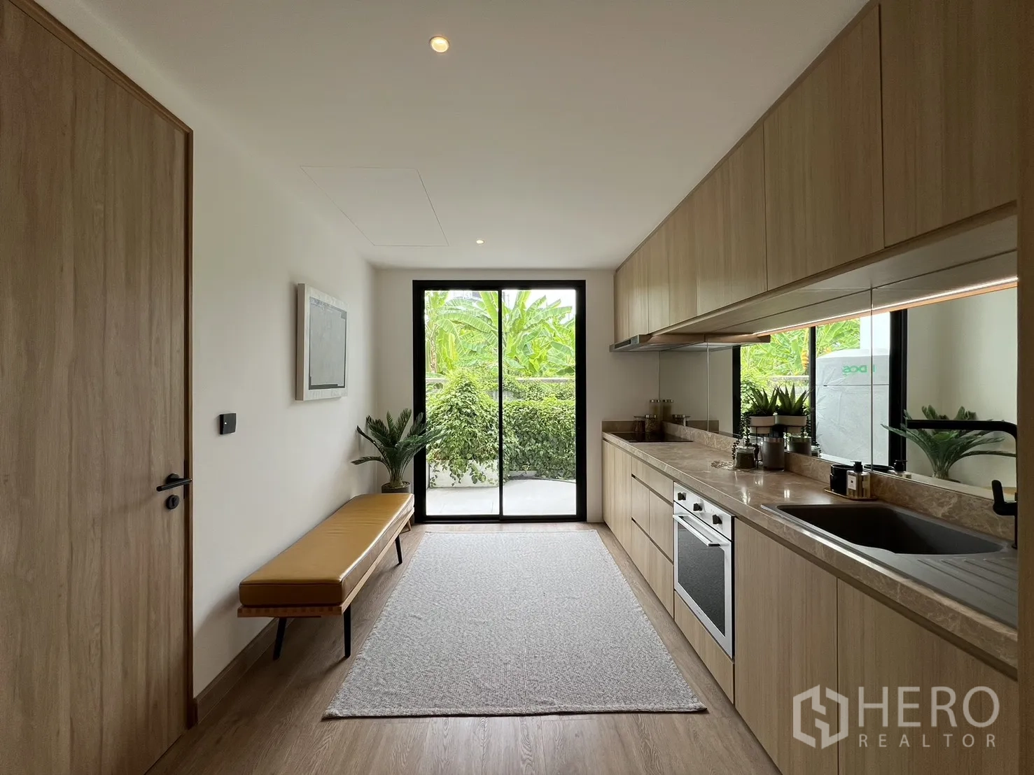 Townhouse for sale in Watthana, Bangkok - Island kitchen facing the staircase with bedroom entrance and rear garden view.
