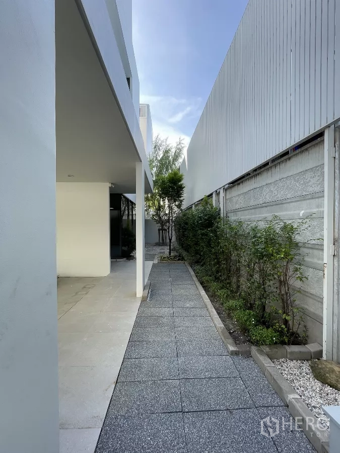 Home Office for rent in Don Mueang, Bangkok - Side walkway with pavers, shrubs and a covered patio along the house.