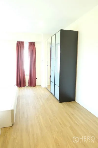 Home Office for rent in Wang Thonglang, Bangkok - Spacious bedroom with wardrobe and red curtains allowing natural light.