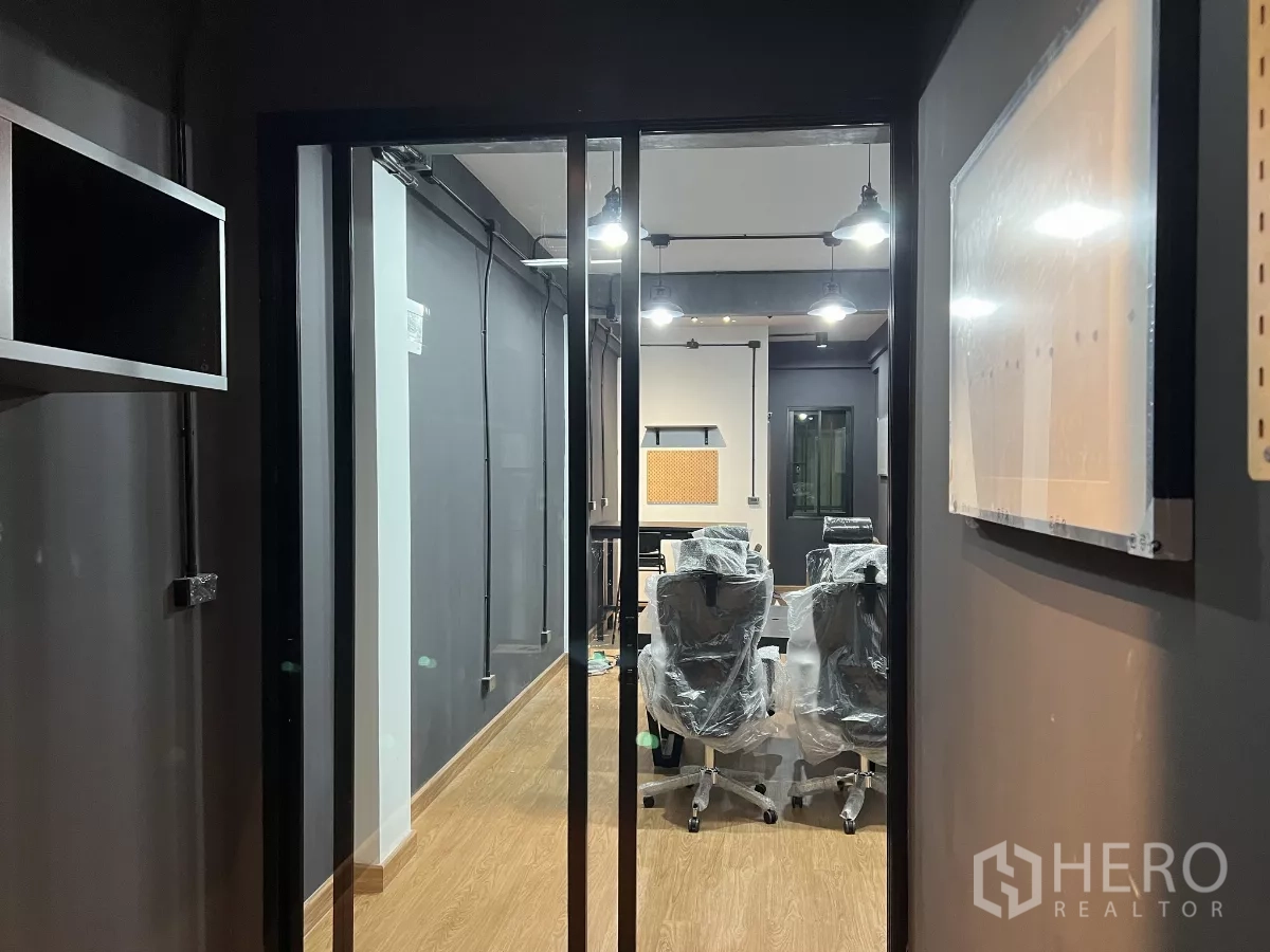 Home Office for rent in Pom Prap Sattru Phai, Bangkok - Glass entry doors reveal an industrial‑style office with wood floors and pendant lighting.