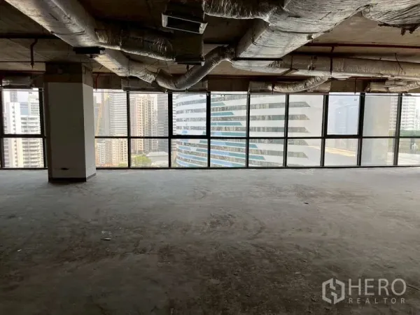 Office Space for rent - Open-plan office floor with exposed HVAC ducts and panoramic windows facing Sukhumvit towers.