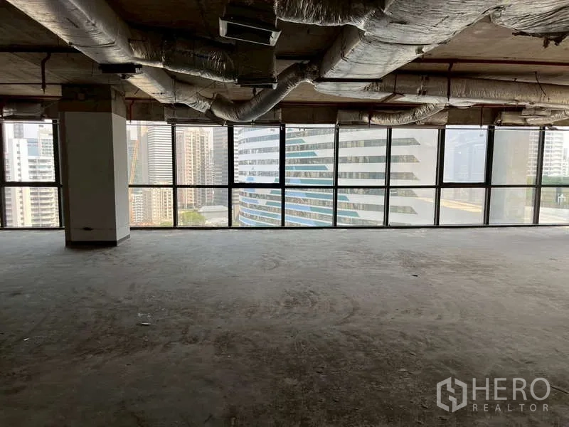 Office Space for rent - Open-plan office floor with exposed HVAC ducts and panoramic windows facing Sukhumvit towers.
