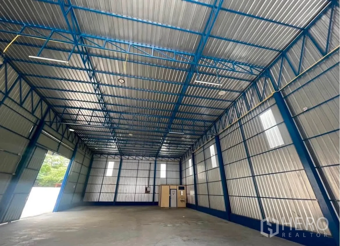 Warehouse for rent in Wang Thonglang, Bangkok - Ceiling view of the warehouse showing steel trusses and lighting fixtures.