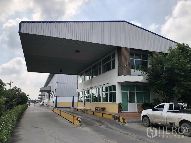 Warehouse for rent in Phra Nakhon Si Ayutthaya - Office building with deep canopy and raised loading platform along the driveway.
