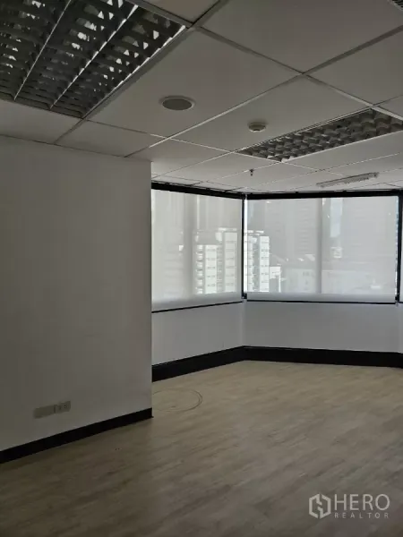 办公空间 出租在Watthana, Bangkok - 开放式办公区，大转角窗带城市景观与遮光帘，天花荧光灯。