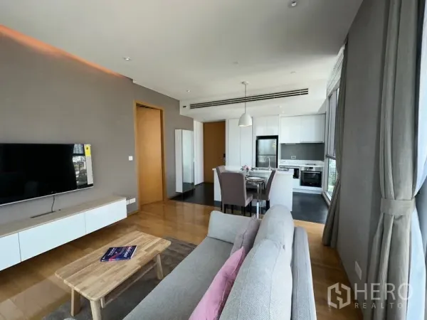 公寓 出租在Watthana, Bangkok - 开放式起居区与现代厨房相连，配有餐桌和落地窗。