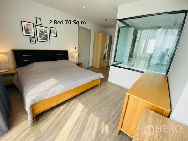 Condominium for rent in Watthana, Bangkok - Primary bedroom with glass-walled bathroom, wood furniture and natural light in Watthana condo.