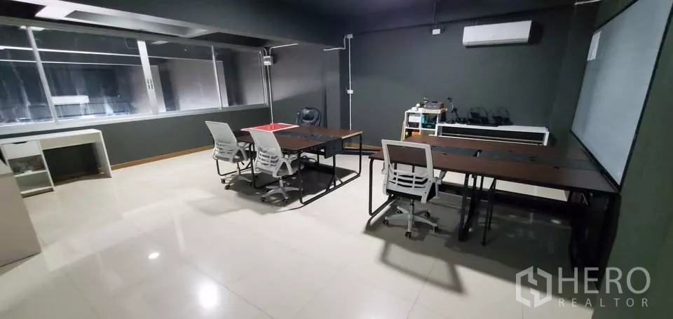 Office Space for rent in Suan Luang, Bangkok - Office room with workstations, dark walls, air conditioning and a large internal window.