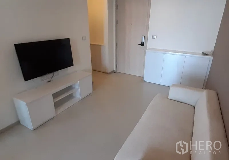 คอนโด ให้เช่าในKhlong Toei, Bangkok - พื้นที่นั่งเล่นมินิมอล ทีวีจอแบนบนตู้สีขาว และประตูทางเข้า