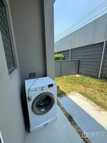 Detached House for rent in Don Mueang, Bangkok - Outdoor laundry area with front-load washing machine and small grass yard.
