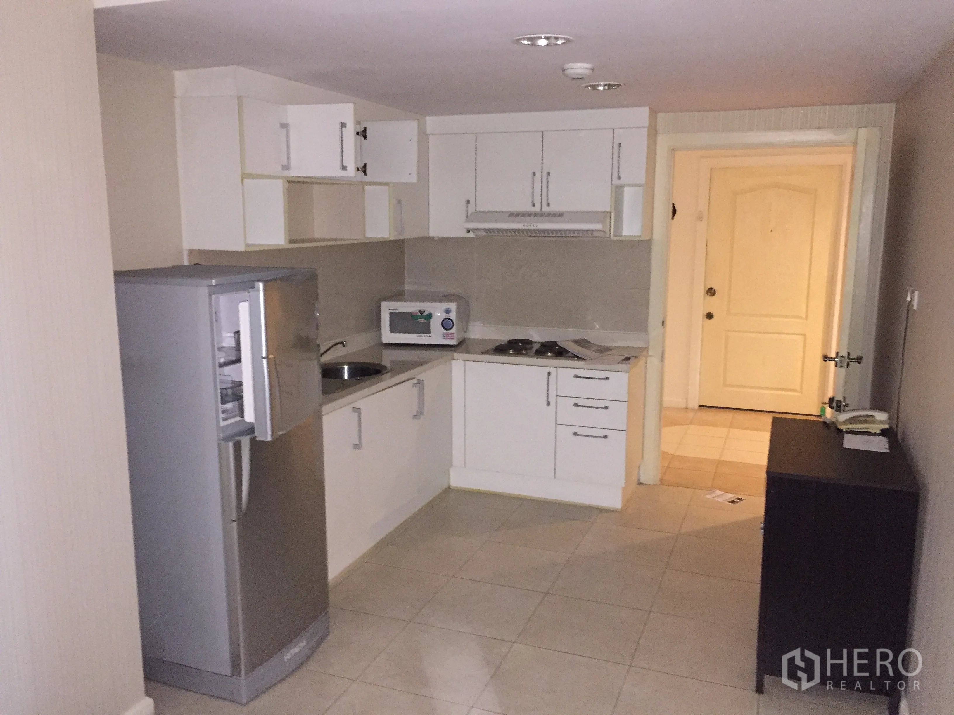 คอนโด ให้เช่าในWatthana, Bangkok - ครัวปิดพร้อมตู้สีขาว เตาและเครื่องดูดควัน ไมโครเวฟ ตู้เย็น และพื้นกระเบื้องใกล้ประตูทางเข้า