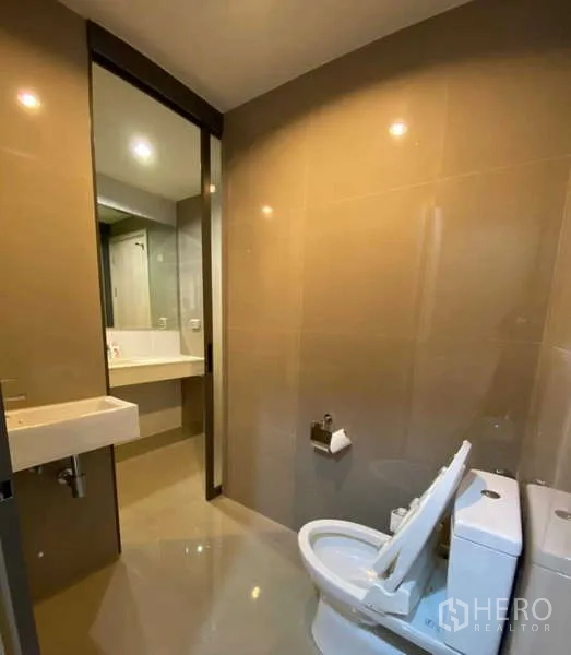 คอนโด ให้เช่าหรือขายในKhlong Toei, Bangkok - โถงสุขภัณฑ์สะอาดพร้อมอ่างล้างหน้า กระเบื้องโทนอบอุ่น มองทะลุไปยังโซนล้างหน้าและฝักบัว