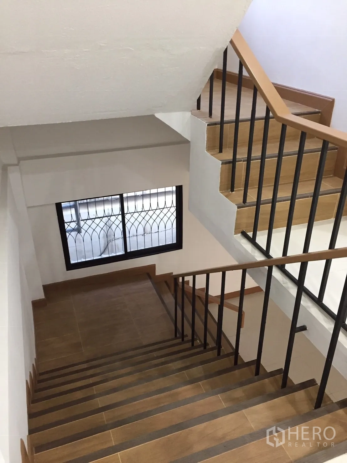 店屋 出租在Suan Luang, Bangkok - 楼梯采用木纹踏步与黑色金属扶手，并配有带护栏的窗户。