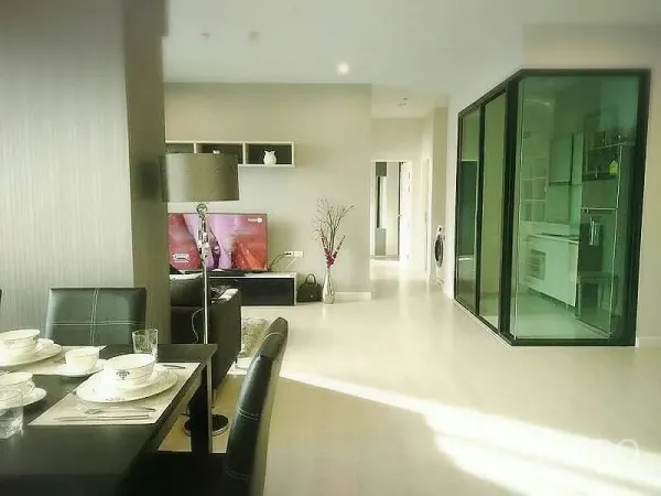 Condominium for rent or sale in Huai Khwang, Bangkok - Open-plan view to TV lounge and glass-partitioned kitchen with built-in appliances.