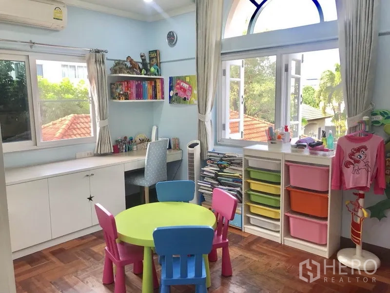 独立式住宅 出租 - 多彩儿童活动室，圆桌椅、收纳柜、内置书桌与拱形窗户。