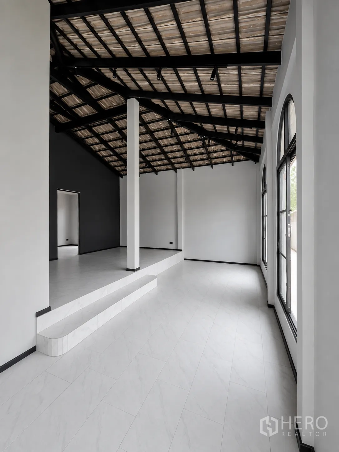 โฮมออฟฟิศ for rent in Phra Khanong, Bangkok - โถงโล่งพร้อมสเต็ปยกระดับ เสา หน้าต่างโค้ง และพื้นกระเบื้องสีขาว ใต้โครงหลังคาเหล็ก