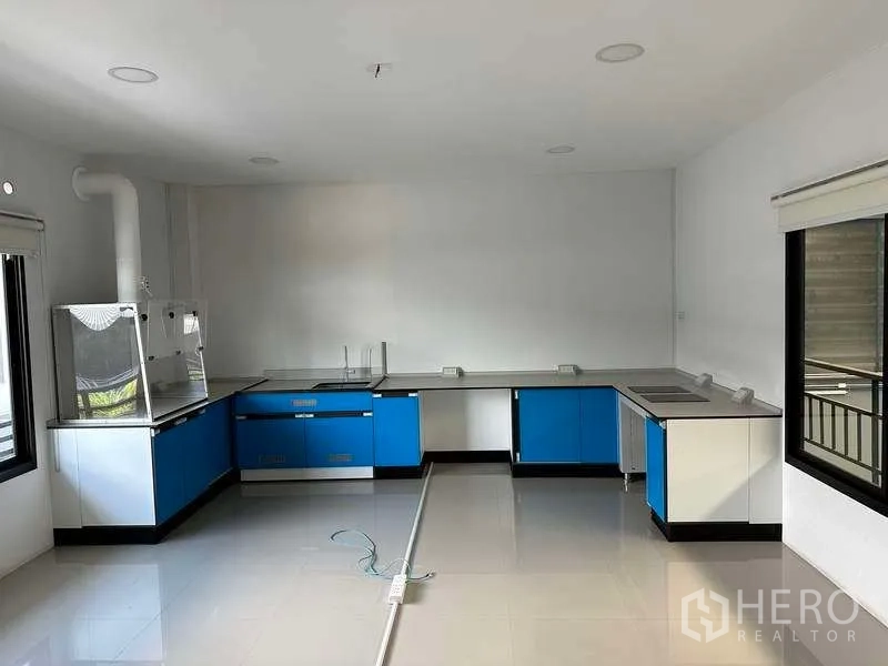 Factory for rent in Samut Prakan - Bright laboratory or pantry room with blue cabinetry and large windows.