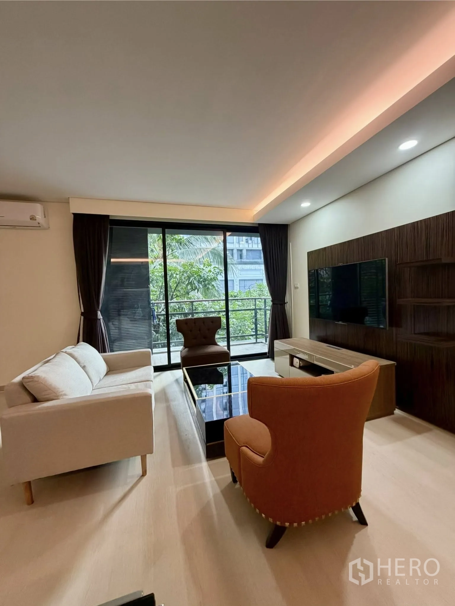 คอนโด for rent in Watthana, Bangkok - พื้นที่นั่งเล่นมีโซฟา ชุดชั้นวางทีวี และประตูกระจกเปิดสู่ระเบียงวิวสีเขียว