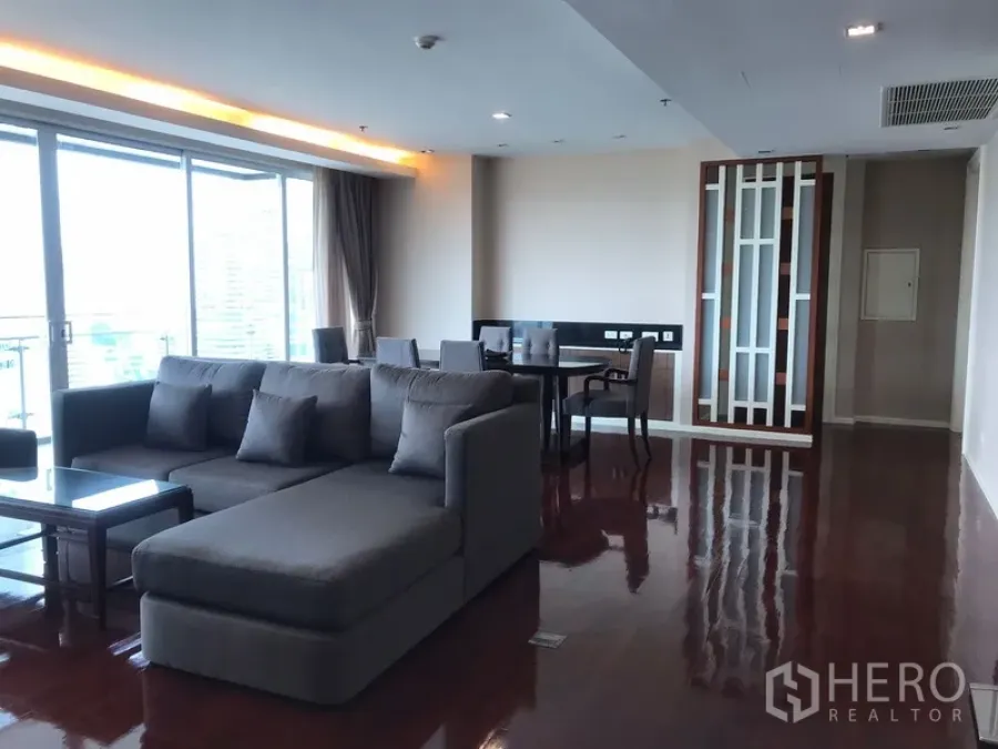 房间 出租在Khlong Toei, Bangkok - 宽敞客餐厅，L型沙发、亮泽木地板与通往阳台的推拉门，空堤区公寓。