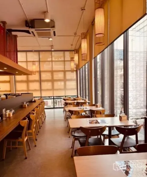 零售空间 出租在Watthana, Bangkok - 高挑层用餐区，整面玻璃立面，木椅与沿墙长吧台。