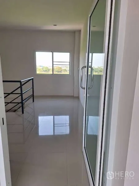 Warehouse for sale in Pathum Thani - Bright upstairs office corridor with a glass door and window outlook.