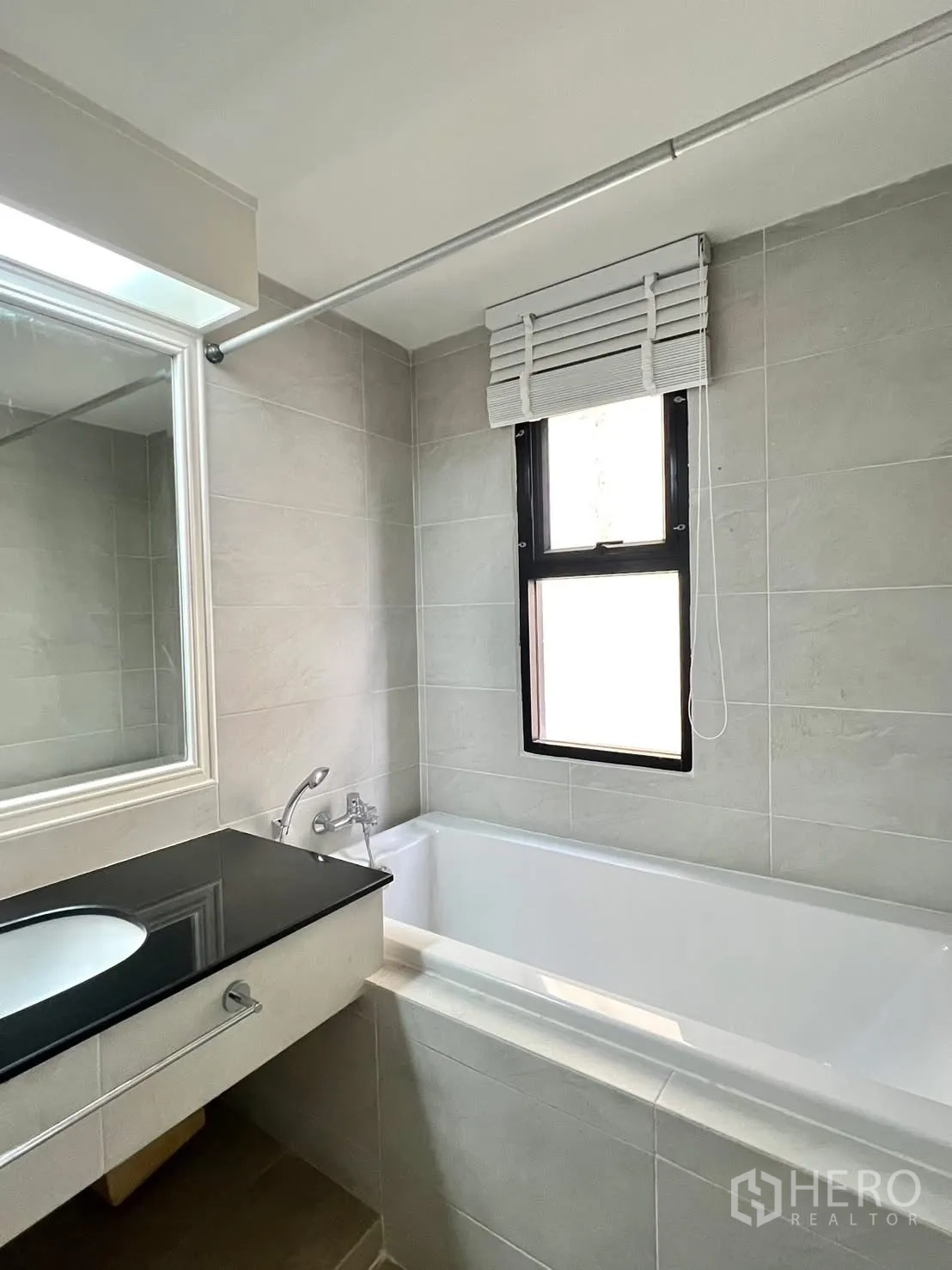 Condominium for rent in Khlong Toei, Bangkok - Bathroom with bathtub, black countertop vanity and a window.