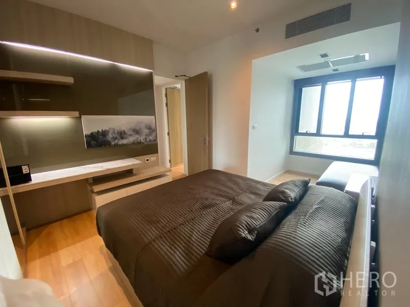 Condominium for rent in Yan Nawa, Bangkok - Bright bedroom with a wide window, feature wall and built-in desk.