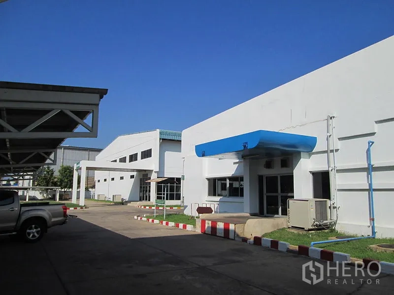 โรงงาน ให้เช่าในPathum Thani - ด้านหน้าอาคารโรงงาน มีกันสาดสีน้ำเงิน ที่จอดรถ และงานระบบครบ