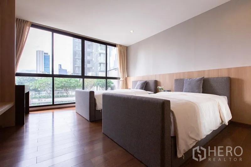 公寓 出售在Sathon, Bangkok - 次卧双床设计，通高玻璃窗外是城市天际线。