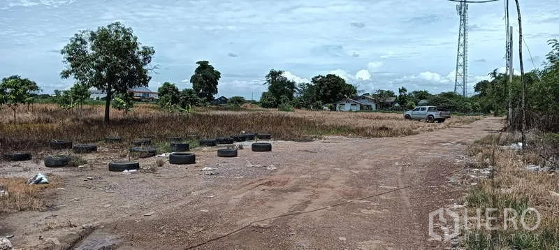 Land for sale in Bang Sao Thong, Samut Prakan - Eight-meter-wide dirt access road across the plot, with a pickup truck and tires marking the boundary.