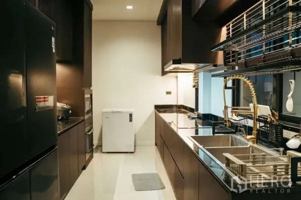 บ้าน ขายในSai Mai, Bangkok - ครัวสไตล์แกลลีโทนเข้ม ท็อปหิน อ่างล้างจานคู่ พร้อมก๊อกฮานส์สีทองแบบดึงลงได้