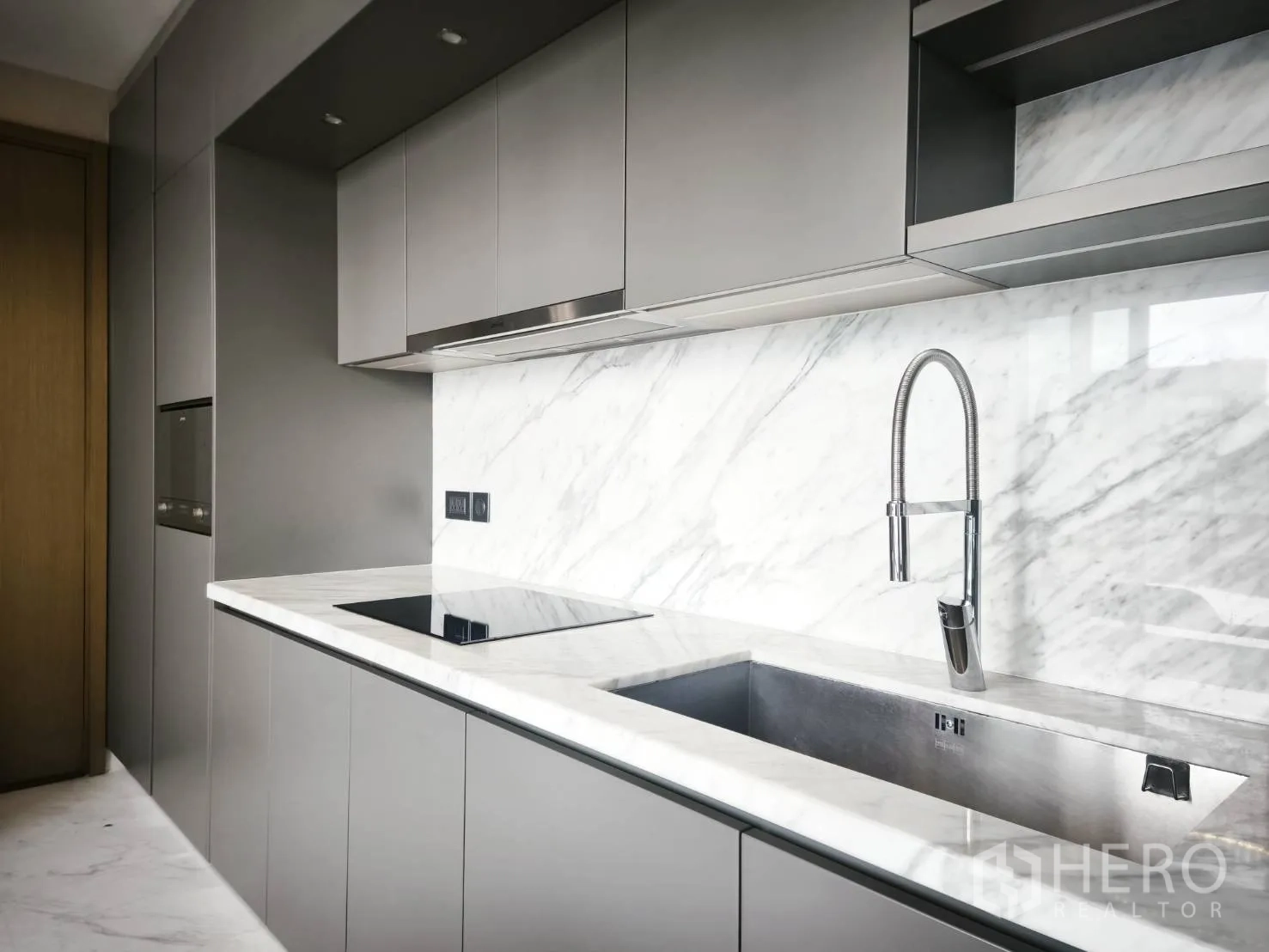 Condominium for rent in Watthana, Bangkok - Sleek kitchen with marble backsplash, induction cooktop, and deep sink.