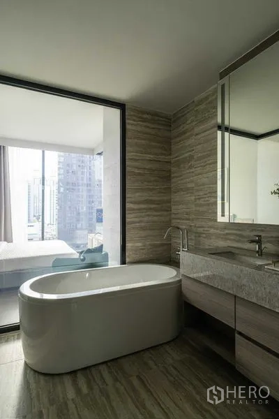 Condominium for rent - Bathroom featuring a freestanding tub beside a window looking into the bedroom and city skyline.