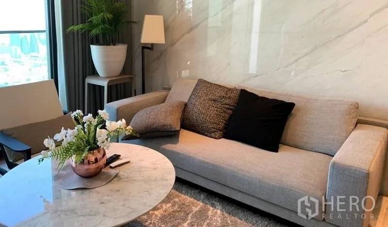 公寓 出售在Khlong San, Bangkok - 温馨客厅，灰色沙发、大理石质感背景墙与圆形大理石茶几。