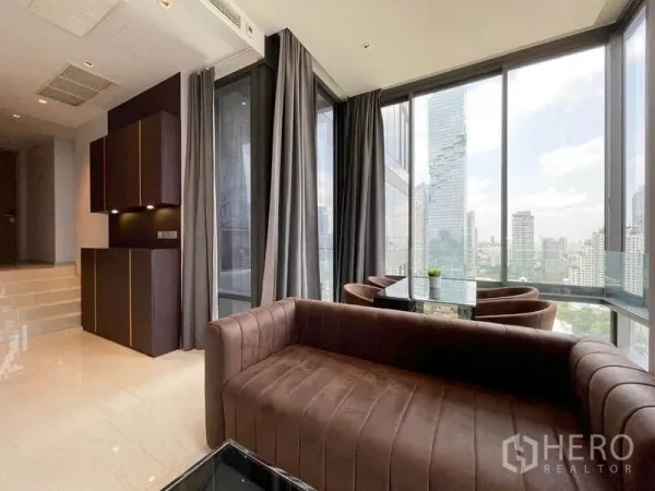 公寓 出租在Bang Rak, Bangkok - 时尚客厅连接全景转角用餐区，四周为落地窗框景。