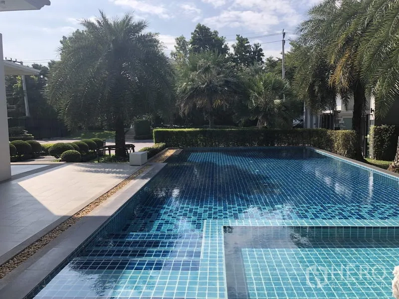 Detached House for rent or sale in Saphan Sung, Bangkok - Communal swimming pool with blue mosaic tiles surrounded by palm trees and gardens.