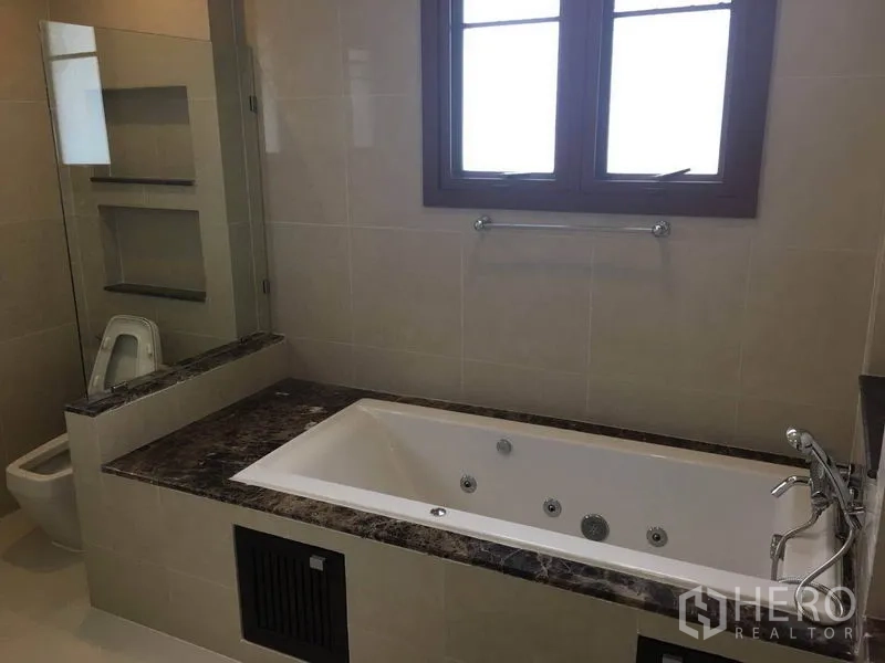 Detached House for rent in Bang Phli, Samut Prakan - Bathroom with marble-trimmed Jacuzzi bathtub, glass partition, and frosted window for privacy.
