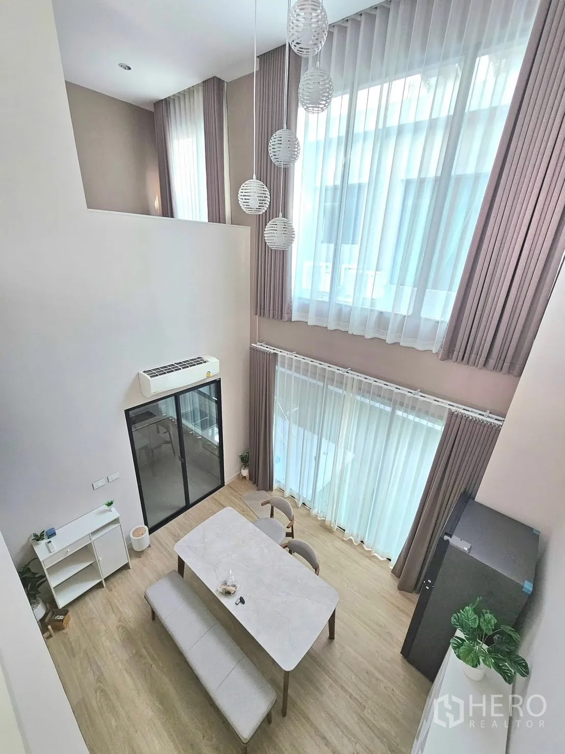 Townhouse for rent in Saphan Sung, Bangkok - Double-height dining area with marble-top table, bench seating, and sliding glass doors.