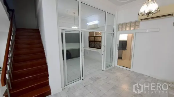 Townhouse for rent in Watthana, Bangkok - Bright living space featuring sliding glass doors and polished wood stairs.